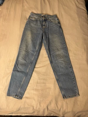 Ljusblå mom jeans - Säljer ett par ljusblå mom jeans.  Jeansen har klassiska fem fickor och dragkedja med knapp. 