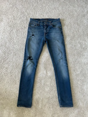 Blåa Nudie Jeans Grim Tim Storlek W29 L32 - Mycket fina Nudie jeans i blå färg. | Jeansen är i mycket bra skick och sparsamt använda. |  Äkta som allt annat jag säljer! ✅ |  Storlek: W29 L32 | Skick: Mycket Bra Skick - har lagningar | Färg: Blå | Märke: Nudie | Modell: Jeans |   Hör gärna av dig vid frågor så svarar jag så fort jag kan! 😁 |  (SKU - 200)