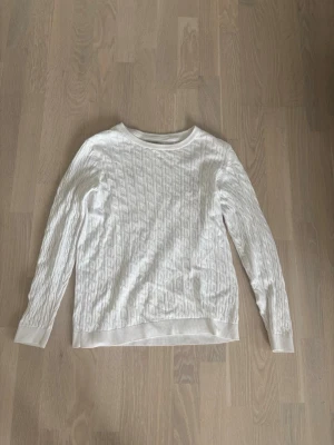 Vit ribbstolar tröja - Ribbstickad vit tröja med rund halsringning och långa ärmar. Tröjan har ett klassiskt mönster och ribbade muddar vid ärmslut och nederkant. Perfekt för lager-på-lager och enkel att matcha med jeans eller kjol. Riktigt grisch och fin med skjorta under för mer uppklädd look. 