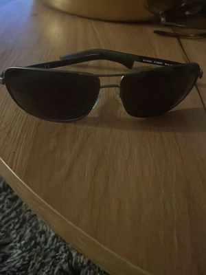 Svarta pilotbågar solglasögon - Snygga solglasögon med klassisk pilotform och svarta bågar. Glasen är mörka och bågarna har metallinslag samt bekväma näskuddar. Perfekta för en cool och tidlös stil. Emporio Armani EA2033