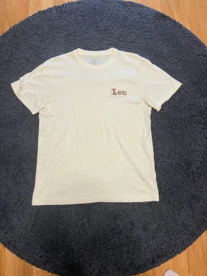 Vit t-shirt från Lee med logga - Säljer en stilren vit t-shirt från Lee i mjuk bomull. T-shirten har korta ärmar och en liten Lee-logga på bröstet. Perfekt basic-plagg som funkar till allt och har en klassisk passform. Sprillans ny