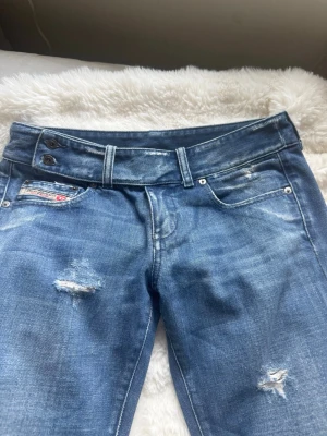 Blå slitna bootcut jeans - Snygga blå jeans med bootcut passform och slitna detaljer på benen. Midjemått: 39 cm rakt över. Innerbenslängd: 75 cm. OBS: står W29 men är väldigt små i storleken så uppskattas mer som W26.🩷🩷🩷