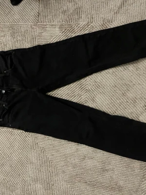 Svarta skinny jeans med hög midja - Storlek 30/32.    Säljer ett par svarta skinny jeans med hög midja och klassisk femficksdesign. Jeansen har smal passform hela vägen ner och är tillverkade i stretchigt material för extra komfort. Perfekta till en avslappnad eller trendig look.