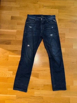 Slitna Replay Jeans - Mörkblå Replay jeans i modell Thad i storlek 12A (barn modell) vilket motsvara ca L28 W27. Jeansen har en fade och slitningar, de är även i ett väldigt bra skick. Nypris ca 800, kom hjärna med prisförlag!
