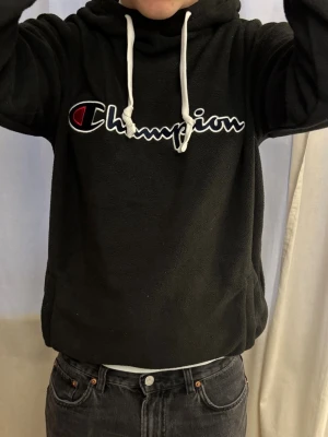 Svart Championhoodie - Svart hoodie från Champion i fleecematerial. Har något form av gummiband som kan dras åt längst ner.