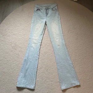 Ljusblå bootcut jeans med hög midja - Snygga ljusblå jeans med bootcut och hög midja. Klassisk femficksmodell med dragkedja och knapp framtill. Jeansen har en lätt utsvängd passform nertill och är tillverkade i mjukt denimtyg. Perfekta för dig som gillar retrovibbar och vill ha en bekväm stil.