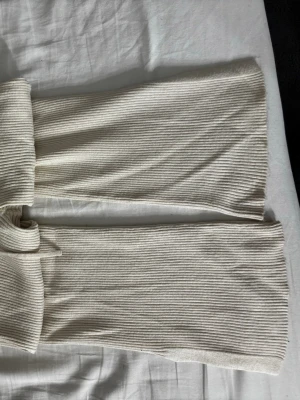 Beiga ribbade mjukisbyxor med knyt - Säljer ett par beiga ribbade mjukisbyxor med breda ben och knytband i midjan. Byxorna är i mjukt och stretchigt material, perfekta för chill dagar hemma. Snygg ribbad struktur som ger en trendig look.