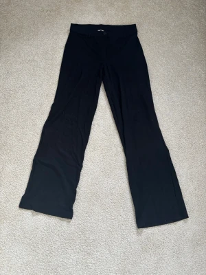 Svarta vida kostymbyxor - Snygga svarta kostymbyxor med vida ben från Nelly. Byxorna har knapp och dragkedja framtill och är tillverkade i ett mjukt, tunt matrial. 