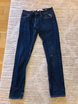 Mörkblå skinny jeans från Replay - Snygga mörkblå skinny jeans från Replay med klassisk femficksmodell och guldfärgade detaljer. Jeansen har normal midja och smal passform hela vägen ner. Perfekta till en avslappnad streetstyle-look.