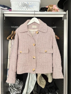 Rosa tweedjacka  - Säljer en snygg rosa tweedjacka från Neo Noir där den är fåtals använd men väl tagen hand om. Man kan se det hamnat lite smuts på själva lappen som man ser i andra bilden. Men det syns ej när man väl har jackan på. Vet ej tyvärr storlek men gissar på S/M!❣️