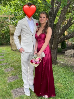 Jättefin vinröd balklänning 😍 - Elegant vinröd långklänning i satin med v-ringad front och smala axelband. Klänningen har snörning i ryggen och en öppen ryggdesign som ger en snygg detalj. Perfekt för student eller bal. Är 167 cm och passade perfekt i längd med klackar. Endast använd en gång så i mycket bra skick! ❤️