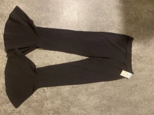 Svarta utsvängda leggings från Kappahl - Säljer ett par svarta leggings från Kappahl med trendiga utsvängda ben. De är mjuka och stretchiga, perfekta för dig som gillar en bekväm men snygg stil. Passar till sneakers eller boots och är lätta att matcha med olika toppar.