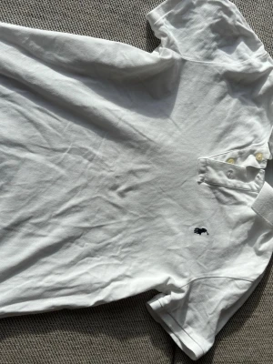 Vit piké från Polo Ralph Lauren -  Vit pikétröja från Polo Ralph Lauren sort slim fit. Klassisk krage med knappar vid halsen samt den ikoniska broderade loggan på bröst. Perfekt basic till garderoben och lätt att match