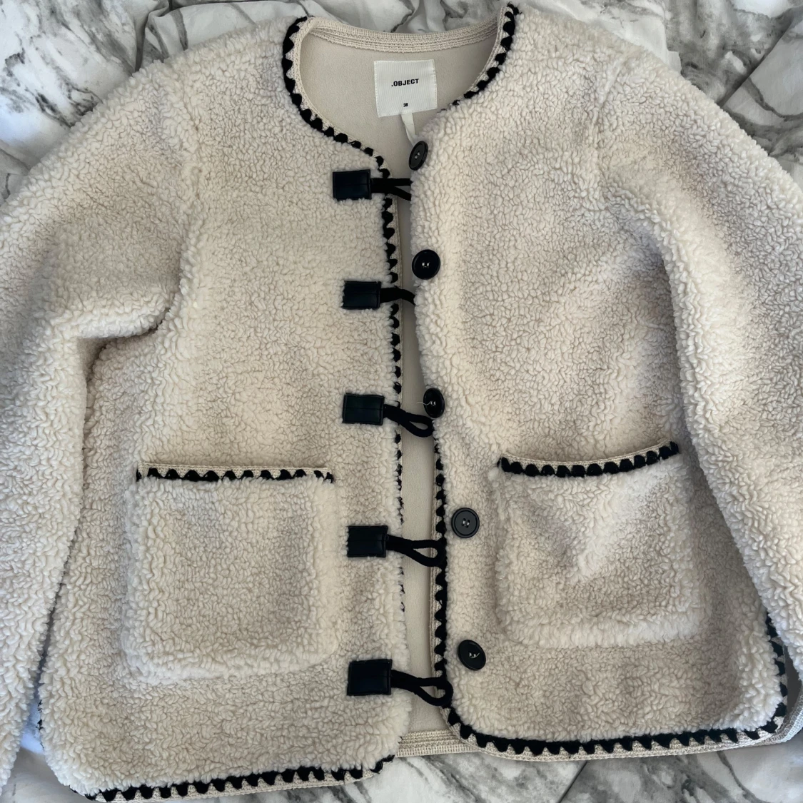 Vit teddyjacka med svarta detaljer