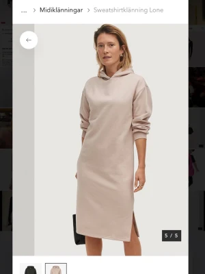 Beige klänning med huva - Hoodieklänning i beige färg med lång ärm och huva. Klänningen har en rak passform och slits på sidan och mycket skönt material. Endast testad!