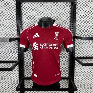 Liverpool matchtröja vinröd Adidas - Snygg vinröd Liverpool FC matchtröja från Adidas med vita detaljer och klubbmärke på bröstet. Tröjan har korta ärmar, rund hals och tryckt sponsorlogga framtill. Perfekt för dig som älskar fotboll och vill representera ditt lag.