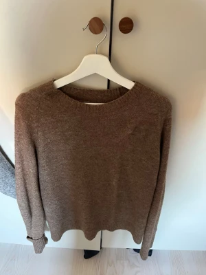 Brun stickad tröja  - Säljer en stilren brun stickad tröja från Whyred. Tröjan har rund halsringning, långa ärmar och ribbade muddar vid ärmslut och nederkant. 