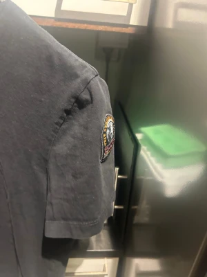 Svart t-shirt från Parajumpers - Klassisk svart t-shirt från Parajumpers med rund hals och korta ärmar. T-shirten har en snygg patch med logga på ena ärmen