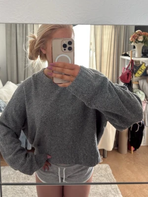 Grå oversized stickad tröja - Mysig grå stickad tröja med oversized passform och långa ärmar. Perfekt för att slappa hemma eller när du vill ha något bekvämt och stilrent. Enkel rund halsringning och mjukt material som känns skönt mot huden.