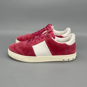 Valentino Flycrew Röd - Snygga sneakers från Valentino i röd mocka med vita detaljer och vita sulor. Skorna har rosa snören, vita partier på sidan och coola nitar på hälen. Perfekta för dig som vill sticka ut med stilrena och trendiga skor.