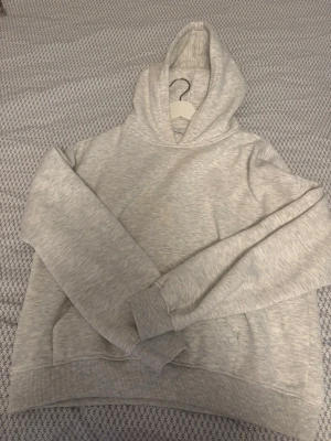 Ljusgrå hoodie från 157 - En stilren ljusgrå hoodie från 157 i storlek M. Hoodien har en klassisk passform med huva och ribbade muddar vid ärmslut och nederkant. Perfekt för en avslappnad look och enkel att matcha med andra plagg.