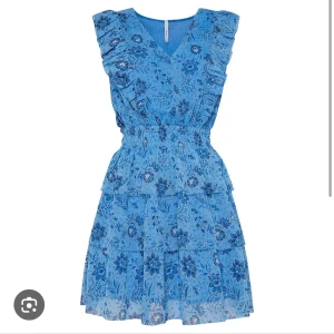 Blå blommig volangklänning - Superfin söt blå kortklänning med blommigt mönster och volangdetaljer. Från pepejeans. Klänningen har v-ringning, resår i midjan och är ärmlös. Perfekt för sommarens alla tillfällen.