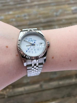 Seiko mod klocka - Unik klocka i silverfärgat metall med länkarmband och vit urtavla. På tavlan står det 'Who cares I'm already late' och siffrorna är utspridda i en lekfull stil. K (