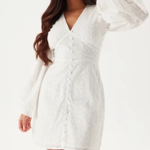 Vit kort klänning med spetsdetaljer - Supersöt vit kortklänning med v-ringning och långa puffärmar. Klänningen har fina spetsdetaljer och knappar framtill. Passar perfekt till studenten! Jag säljer denna klänning då den inte kommer att komma till användning. Den är helt oanvänd och lappen sitter kvar. Storleken är S/36. Nypris för denna är 699 och jag säljer den för 500kr 