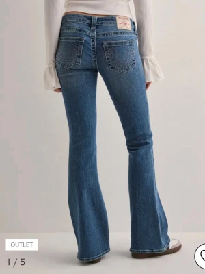 True Religion jeans - Säljer ett par klassiska blå bootcut jeans från True Religion med ikoniska kontrastsömmar och broderade bakfickor. Jeansen har låg midja, fem fickor och är tillverkade i mjuk denim med lätt stretch. Perfekta för en avslappnad och trendig look. Den är i strl 28 men är lite insydd i midjan. Lite slitna längst ner, därav priset💗