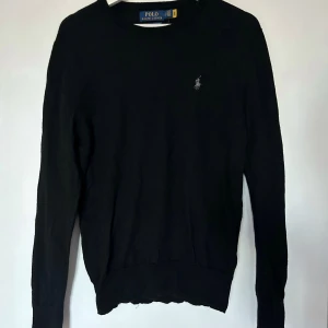 Svart tröja från Polo Ralph Lauren - Säljer en stilren svart tröja från Polo Ralph Lauren i merinoull. Tröjan har en klassisk design med rund hals och långa ärmar. Perfekt för en elegant och avslappnad look. Köpt på Ralph laurens egna butik, nypris ca 2000kr. Hör av dig om du undrar något!