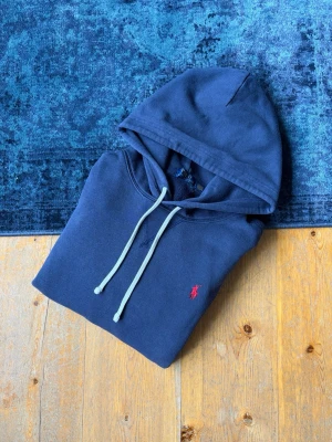 Marinblå Ralph Lauren Hoodie - Hej!👋  Säljer en mörkblå Ralph Lauren Hoodie med den broderade röda pony-loggan på bröstet. Hoodien är I mycket fint skick, och är i princip som ny! Storlek L. Skickar snabbt. Hör av er vid frågor!💯