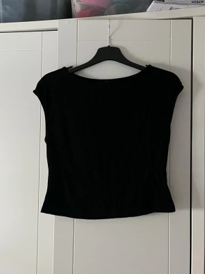 Svart croppad topp med kort ärm - En stilren svart croppad topp med korta ärmar och rund halsringning. Perfekt att matcha med höga jeans eller kjol för en trendig look. Enkel design som passar till många olika outfits.