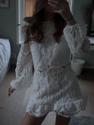 Vit spetsklänning med volang - Söt vit kortklänning i spets med volangdetaljer och långärmade ärmar. Säljer då den var lite för stor. 