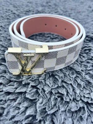 vit rutigt bälte - Tja, säljer ett riktigt fett L-V bälte i färgen vit, bältet är 110 cm. Skriv om du har några funderingar :)