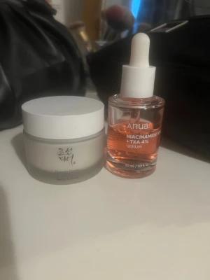 Anua serum & beauty of joseon kräm - Säljer Anua Niacinamide 10% + TXA 4% serum (60% kvar)i glasflaska med pipett och Beauty of Joseon Dynasty Cream i vit burk. Serumet är genomskinligt rosa och krämen är vit och krämig. Perfekt för dig som vill boosta din hudvårdsrutin.
