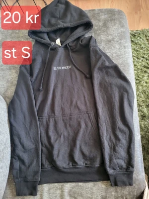 Svart hoodie med tryck framtill - Svart hoodie med huva och dragsnören samt en stor magficka. På bröstet finns ett vitt tryck med romerska siffror 'III.VII.MMXXI'. Hoodien har ribbade muddar vid ärmar och nederkant. Perfekt för en avslappnad och stilren look.