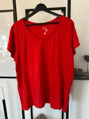 Röd v-ringad t-shirt Basic U XL - En enkel och snygg röd t-shirt från Basic U i storlek XL. T-shirten har v-ringning och korta ärmar, perfekt för en avslappnad stil. Tillverkad i mjuk bomull som känns skön mot huden.