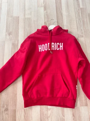 Röd hoodie från Hoodrich - Snygg röd hoodie från Hoodrich med vit logga tryckt på bröstet. 