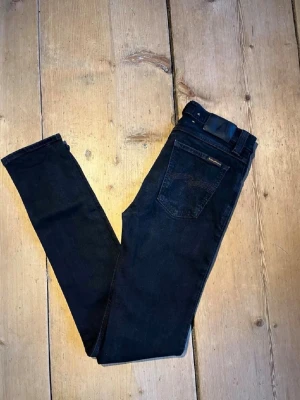 Mörkblå nya nudie jeans W30 L34 - Säljer ett par mörkblå jeans från Nudie. Jeansen har klassisk femficksdesign, smal passform och är tillverkade i stretchigt denimtyg för extra komfort. Perfekta för dig som gillar en snygg och enkel stil.