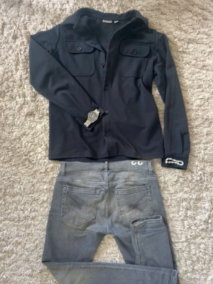 Mörkblå Overshirt från Only & Sons - Stilren mörkblå overshirt från Only & Sons med klassisk krage och två bröstfickor med knappar. Skjortan har långa ärmar och knäppning framtill. Perfekt för en clean och modern look.