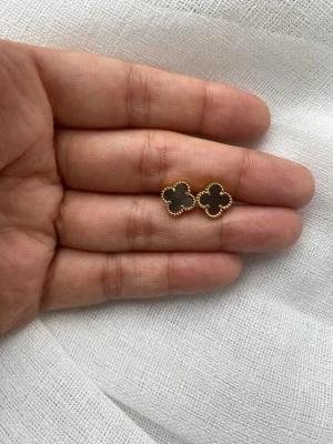 Guldpläterade fyrklöverörhängen - Snygga örhängen i form av fyrklöver med guldfärgad kant och pärlemorskimrande inlägg, en i svart och en i vit. Klassisk och elegant design som ger en lyxig touch till din stil. Perfekta för dig som gillar detaljer och vill sticka ut.