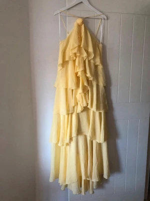 Ljusgul volangklänning med halterneck - Supersöt ljusgul halterneck- långklänning med volanger, storlek M