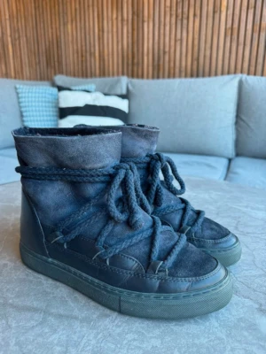 Mörkblå moon boots från Inuikii - Säljer ett par mörkblå moon boots från Inuikii med grova snören och högt skaft. Skorna har en robust gummisula och ovandel i mocka och läder. Perfekta för kalla dagar när du vill ha både stil och värme. Det är bytta ett par sulor inne så att fluffet inuti är mindre nött
