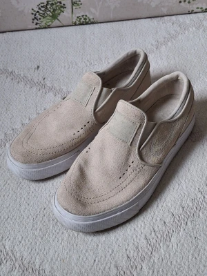 Beige slip-on sneakers från Nike - Snygga slip-on sneakers från Nike i beige mocka och vita sulor.