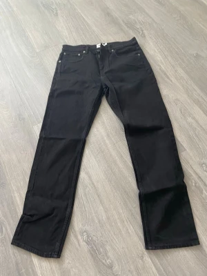 Svarta raka jeans - Snygga svarta jeans med rak passform och klassisk femficksdesign. Jeansen har normal midja och är tillverkade i ett mjukt denimtyg som ger en clean och stilren look. Perfekta att matcha med en hoodie eller t-shirt för en avslappnad vibe.