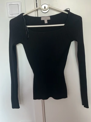 Svart ribbad långärmad topp - Säljer en svart ribbad topp med lång ärm och rundad urringning. Toppen har en tight passform och är tillverkad i stretchigt material som sitter snyggt på kroppen. Perfekt att styla med jeans eller kjol för en clean look.