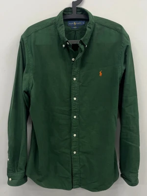 Ralph Lauren skjorta - Riktigt fet mörkgrön färg som passar till alla säsonger. Väldigt fint skick utan defekter, modellen är 185 cm lång och väger ca 75 kg. Slimfit passform i storlek L. 