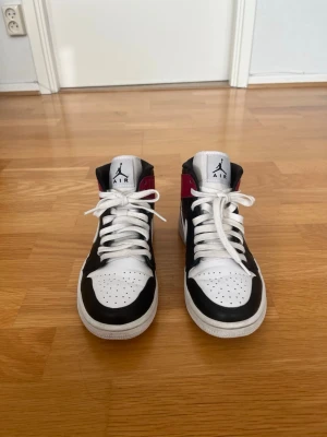 Nike Air Jordan 1 Mid skor - Storlek 38.5 - Säljer ett par Air Jordan 1 Mid i den snygga och tidlösa färgkombinationen svart, vit och röd. Skorna är i bra använt skick med normalt slitage och har fortfarande mycket kvar att ge. De passar lika bra till vardags som för dig som gillar sneakers och streetwear. Storlek EU 38,5. Skorna är rena, bekväma och redo att användas direkt.