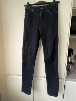 Mörkblå raka jeans - Säljer ett par mörkblå jeans med raka ben och klassiska kontrastsömmar. Jeansen har fem fickor och gylf med knappstängning. Materialet är kraftig denim utan blekning. 