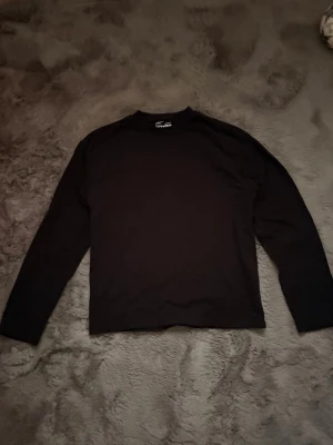 Svart longsleeve tröja från weekday - En enkel och stilren svart långärmad tröja från weekday. Tröjan har en rak passform och är tillverkad i mjuk bomull, perfekt för att matcha med jeans eller joggers. Klassisk rund hals och diskret design som funkar till många olika outfits.
